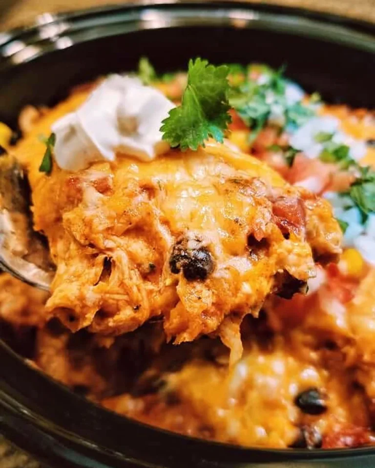 Crockpot chicken enchiladas casserole topped with cheese and cilantro