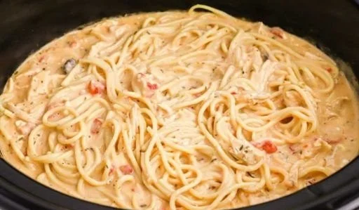 Slow cooker cheesy chicken spaghetti served in a bowl with herbs on top